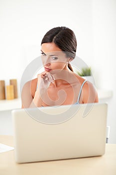 Smart woman thinking while working on computer
