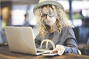 Smart work in travel lifestyle for beautiful trendy caucasian young woman use phone roaming device and laptop computer in bar or