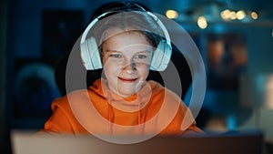 Smart Young Boy in Headphones Using Laptop Computer in Cozy Dark Room at Home. Happy Teenager