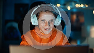 Smart Young Boy in Headphones Using Laptop Computer in Cozy Dark Room at Home. Happy Teenager