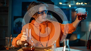 Smart Young Boy in Safety Goggles Mixes Chemicals in Beakers and Checking Results. Teenager