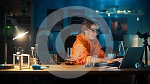 Smart Young Boy in Safety Goggles Write Down Results on a Laptop after Mixing Chemicals in Beakers