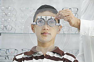 Young boy examining eyesight in optical clinic.