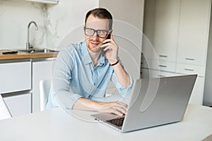 Smart young businessman talks on the phone using laptop