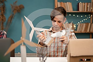 Smart young child work making wind turbines project at home. Boy learning about eco-friendly forms of renewable