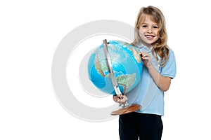 Smart young girl showing her country on a globe