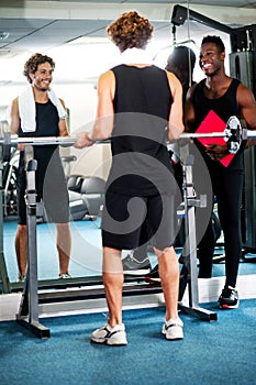 Smart young guy lifting barbells in gym