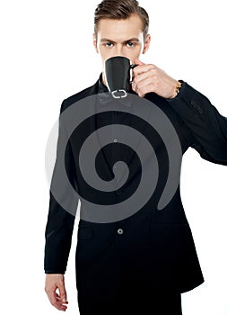 Smart young man drinking coffee in black cup