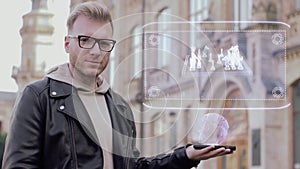 Smart young man with glasses shows a conceptual hologram chessboard with figures