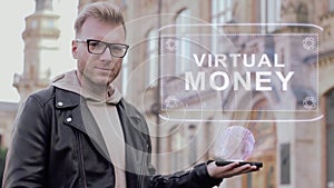 Smart young man with glasses shows a conceptual hologram Virtual money