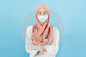 Smart young muslim woman doctor in lab coat with Medical face mask,white latex medical gloves and stethoscope against blue