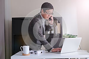 Smart youngadult 40s asian man with eye glasses working on laptop or computer notebook in modern working space. office life and