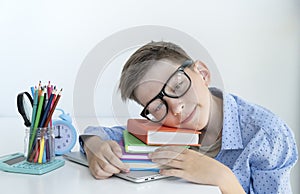 Smart youngster in eyeglasses putting his head on open book