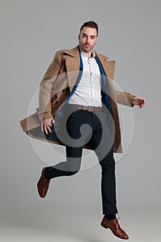 Smartcasual fashion model wearing long coat and jumping