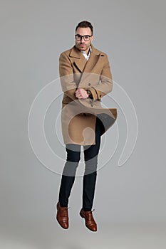 Smartcasual man wearing long coat jumping in the air