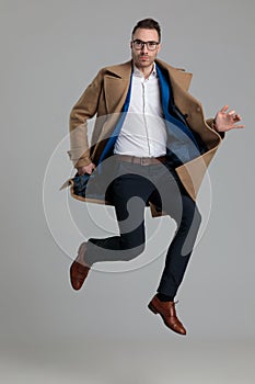 Smartcasual young guy wearing long coat and jumping