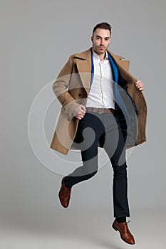 Smartcasual young guy wearing long coat and jumping