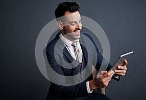 The smartest exec around. Studio shot of a stylish young businessman using a digital tablet against a gray background.