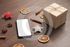 Smarthone with white screen and christmas decorations on walnut table