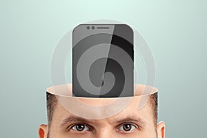 Smartphone addiction, close-up of a man`s head instead of a mobile phone brain. Technology concept, human weakness, addiction.