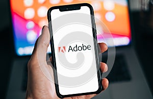 Smartphone with Adobe logo on the screen in hand