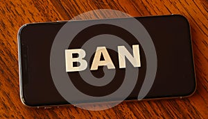 Smartphone and Ban alphabets, on wooden table.