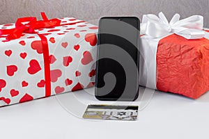 Smartphone with a bank card and Christmas gifts on the table. Online shopping festive internet concept