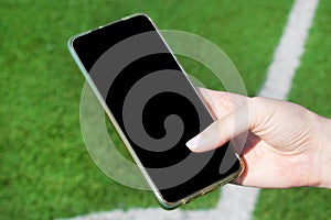 Smartphone with black screen against the soccer field