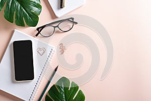 Smartphone, blank notepad, monstera flower leaf, glasses, pen, paper clips, pencil on a light background, top view. Make