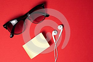 Smartphone with Blank Screen Connects to Earphones with Spiral Cable on Red Background Top View, Sunglasses