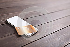 Smartphone with blank screen and credit card on wooden table