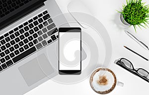 Smartphone with blank screen, laptop, coffee cup, glasses, pen and pencil on white office desk table, top view, workspace design,