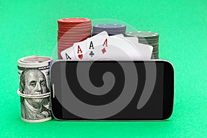 Smartphone with blank screen, poker chips, playing cards and money on green background. Online casino. Space for text