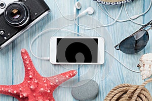 Smartphone and camera on table with starfish and shells