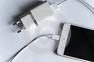 Smartphone with charger on white background
