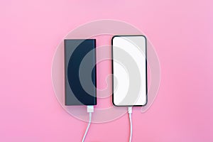 Smartphone charging with power bank on pink background. white screen or blank screen with clipping path for copy space. Flat lay