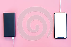 Smartphone charging with power bank on pink background. white screen or blank screen with clipping path for copy space. Flat lay