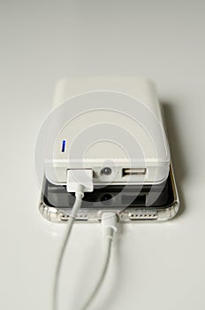 Smartphone charging with power bank on white background