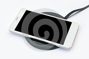 Smartphone charging on a wireless charger on white background. black screen or blank screen with clipping path for copy space.