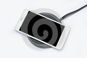 Smartphone charging on a wireless charger on white background. black screen or blank screen with clipping path for copy space.