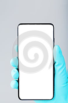 Smartphone with a clean white screen in the hand in a blue medical glove close-up.