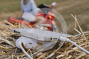 Smartphone close-up with a portable charger. Power Bank charges the phone against the backdrop of a motorcycle, a girl