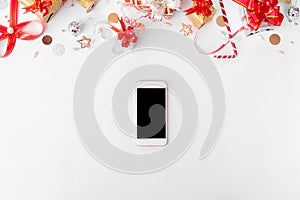 Smartphone composition for christmas time. christmas gifts and decorations on white background.