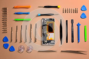 Smartphone cover removed, internals exposed with tools arranged around.