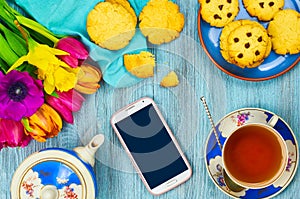 Smartphone and cup of tea with cookies.