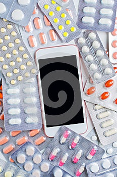 Smartphone with a dark screen. Background of colored pills. The concept of online drugstores. Copy space. photo