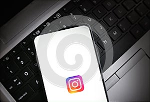 Smartphone displaying Instagram logo on laptop keyboard for social media interaction illustrative