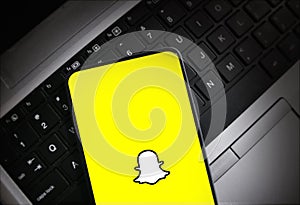 Smartphone displaying Snapchat logo on laptop keyboard background illustrative editorial technology and social media