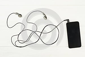 Smartphone with earphones on white background.