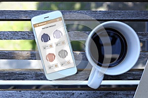 Smartphone with ecommerce website screen and coffee cup